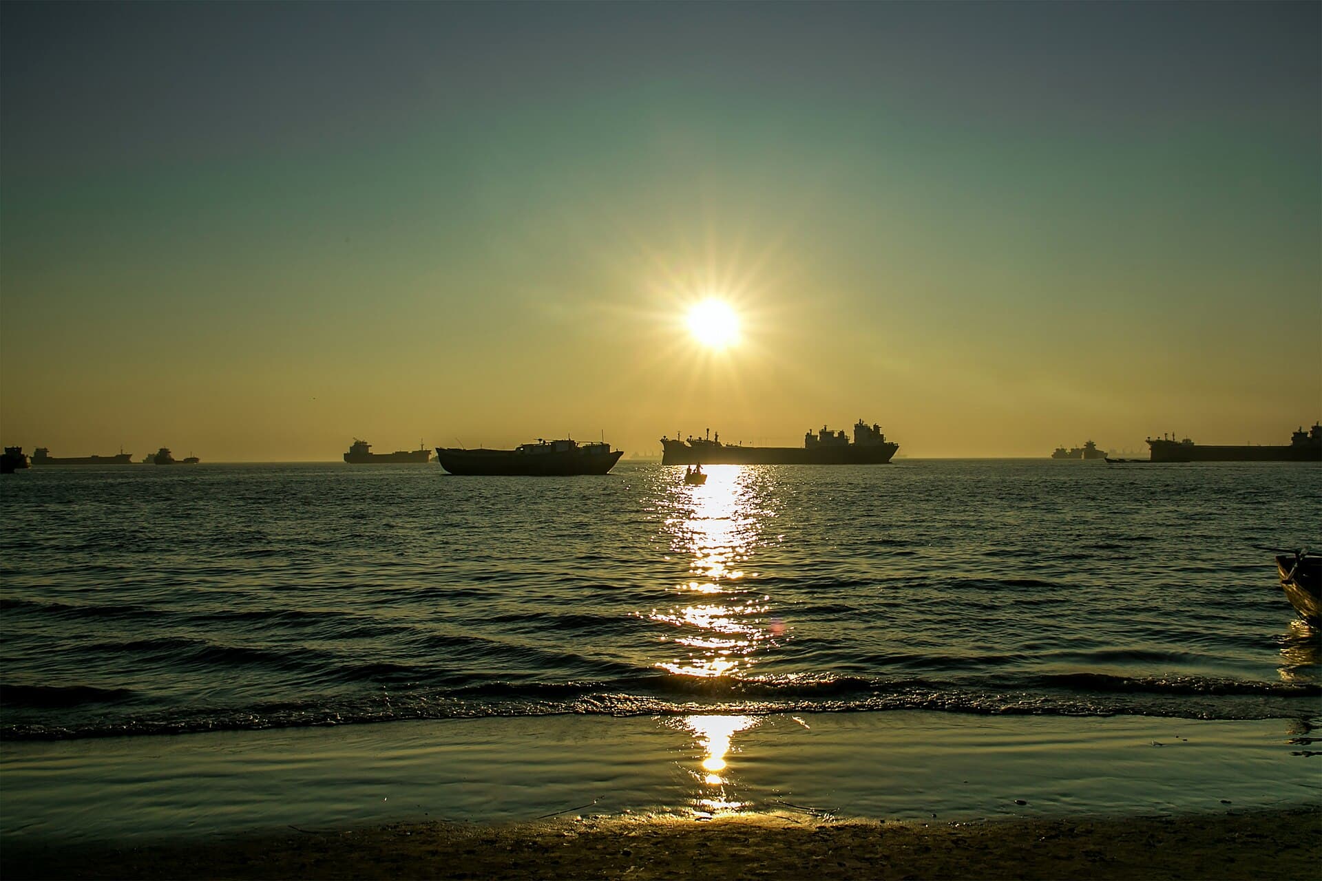 Golden sky and silhouetted visitors at Patenga beach at dusk